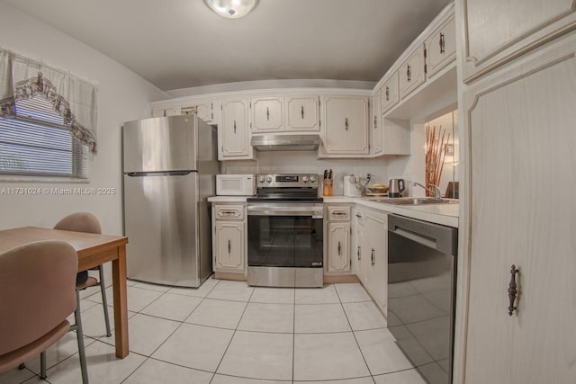 kitchen with appliances with stainless steel finishes, sink, light tile patterned floors, and backsplash