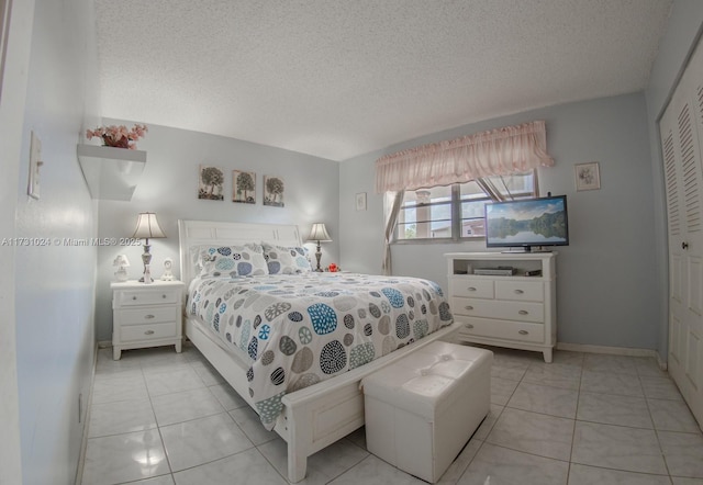 bedroom featuring a closet, light tile patterned floors, and a textured ceiling