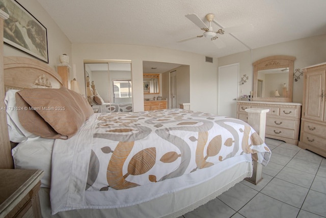 bedroom featuring a closet, ceiling fan, a textured ceiling, and light tile patterned flooring