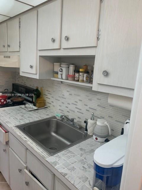 kitchen with tile countertops, tasteful backsplash, extractor fan, and a sink