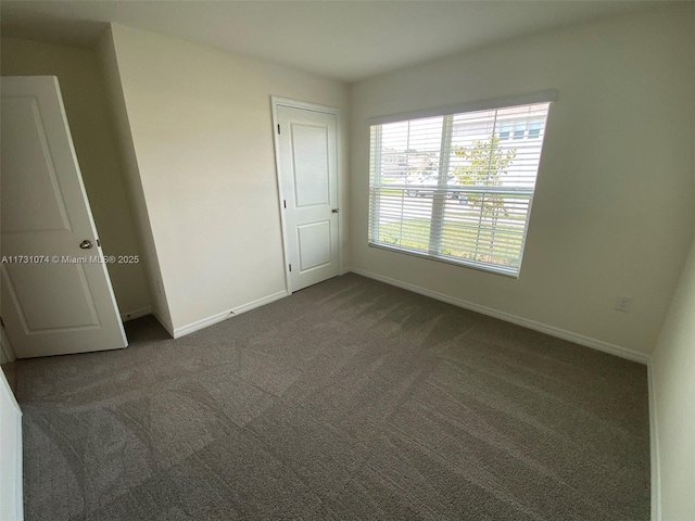 unfurnished bedroom with dark colored carpet and a closet