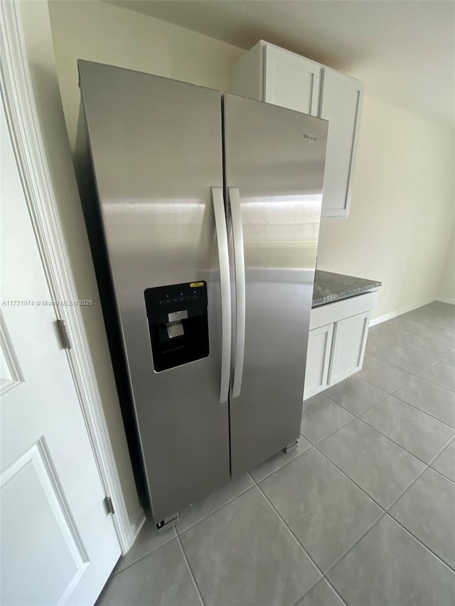 kitchen featuring white cabinetry, stainless steel fridge with ice dispenser, dark stone countertops, and light tile patterned flooring