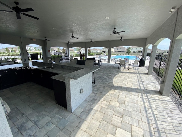 view of patio / terrace featuring a community pool, a wet bar, and ceiling fan