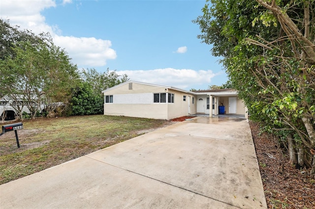 ranch-style house featuring a front lawn and a carport