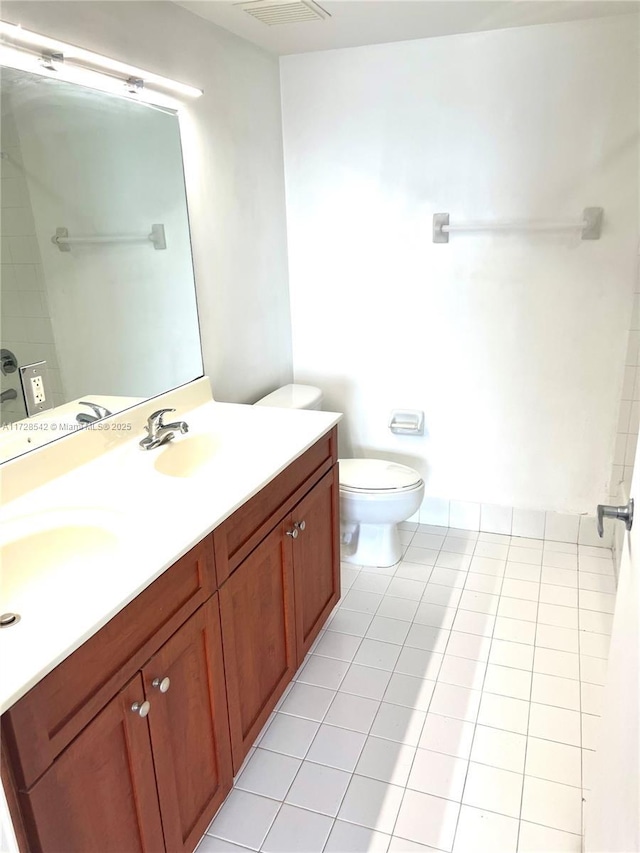 bathroom with toilet, vanity, and tile patterned flooring