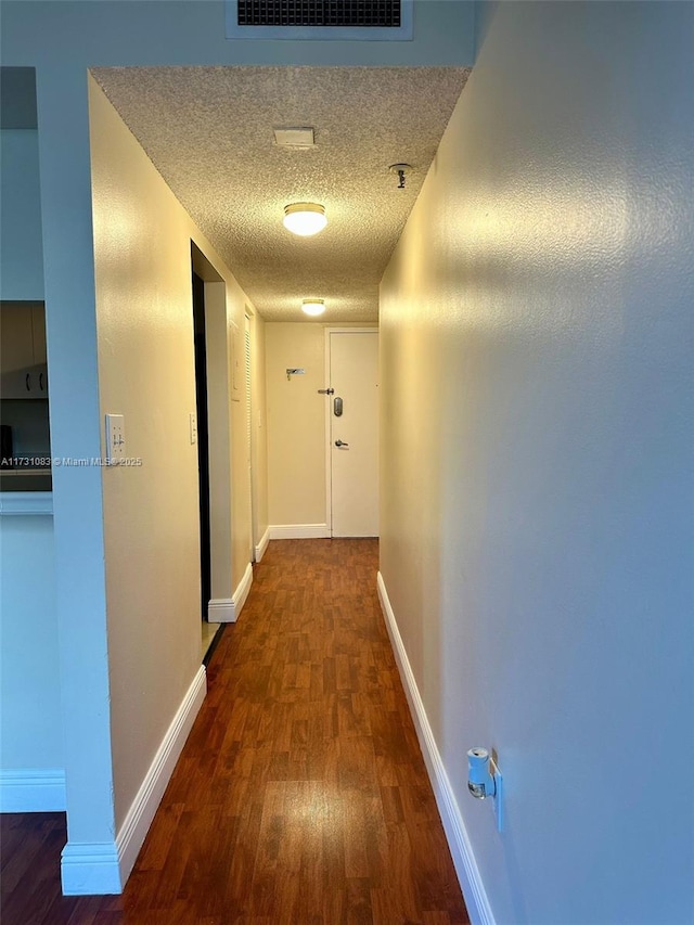 hall featuring dark hardwood / wood-style flooring and a textured ceiling