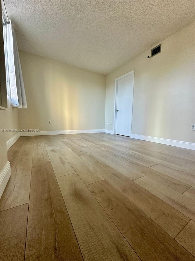 unfurnished room featuring a textured ceiling and light hardwood / wood-style floors