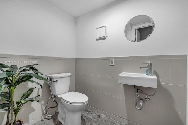 bathroom featuring sink, toilet, and tile walls