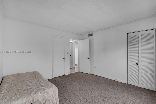 unfurnished bedroom featuring crown molding, a textured ceiling, carpet flooring, and a closet