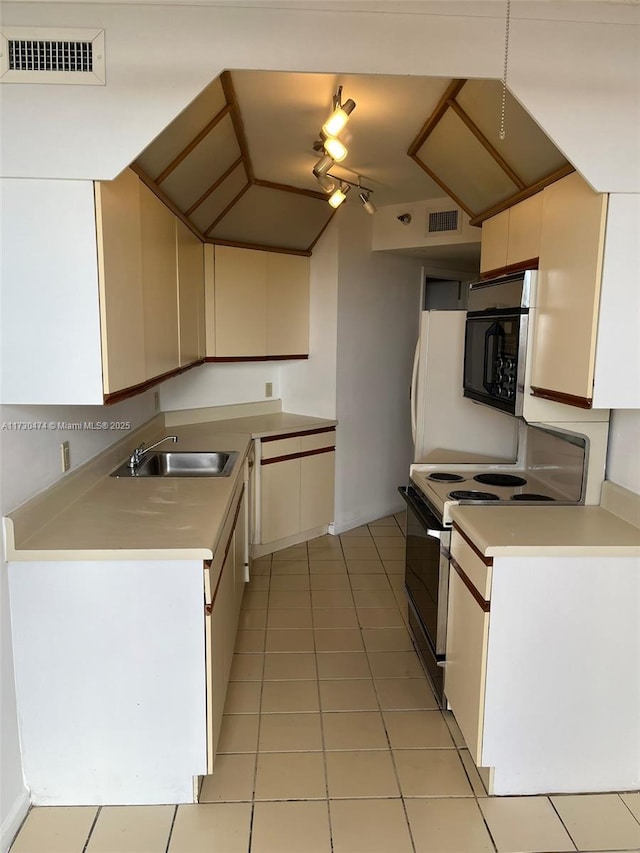 kitchen featuring electric stove, rail lighting, sink, light tile patterned floors, and cream cabinetry