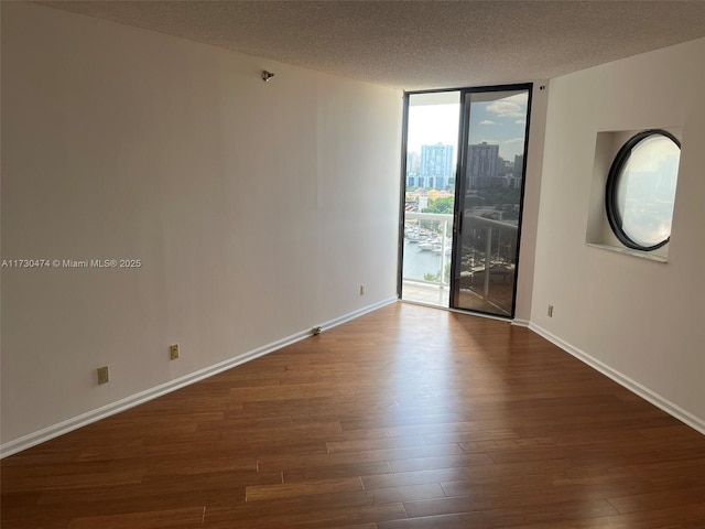 unfurnished room featuring wood-type flooring, floor to ceiling windows, and a textured ceiling