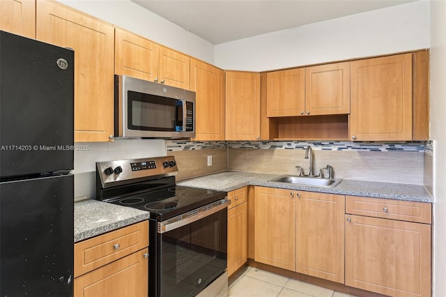 kitchen with sink, light tile patterned floors, appliances with stainless steel finishes, and tasteful backsplash