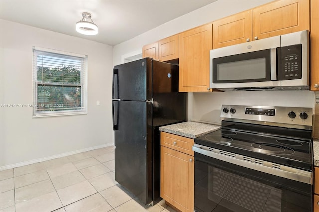 kitchen featuring light stone countertops, stainless steel appliances, light brown cabinetry, and light tile patterned floors