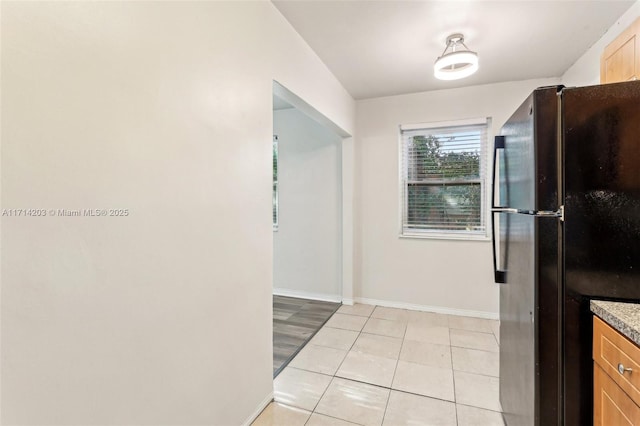 kitchen featuring light tile patterned flooring and black refrigerator