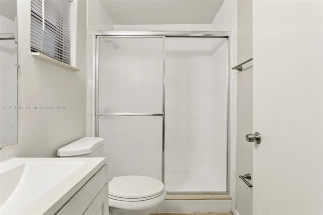 bathroom featuring vanity, toilet, and a shower with door