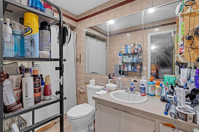 bathroom with curtained shower, toilet, vanity, and tile walls