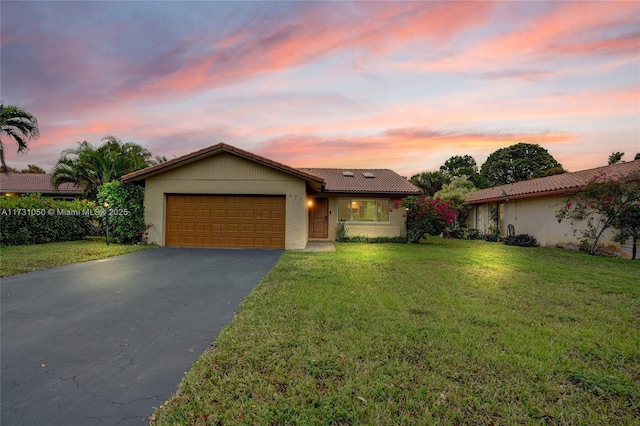 ranch-style house featuring a garage and a lawn