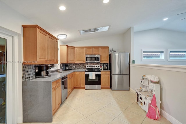 kitchen with vaulted ceiling, appliances with stainless steel finishes, light tile patterned flooring, tasteful backsplash, and sink