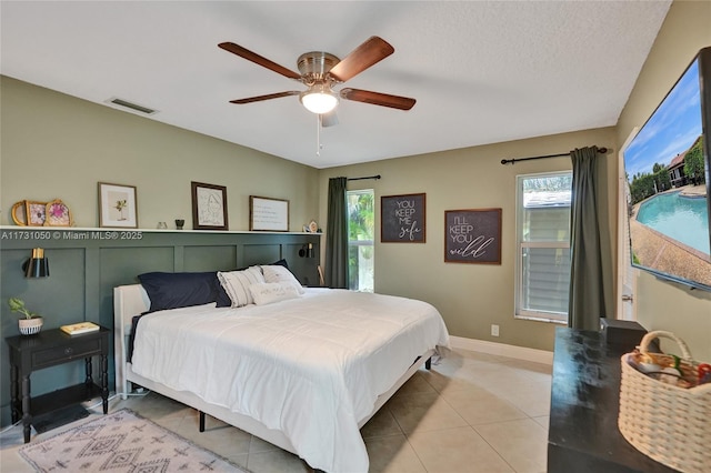 tiled bedroom with a textured ceiling and ceiling fan