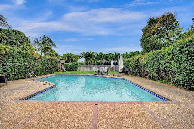 view of swimming pool with a playground and a patio area