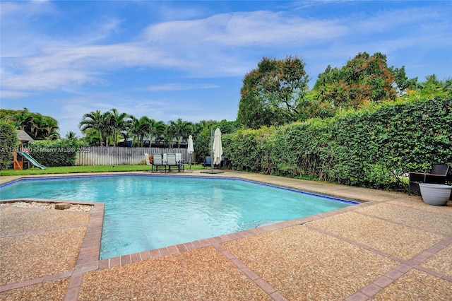 view of swimming pool featuring a patio area and a playground