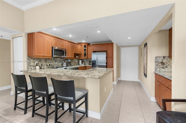 kitchen featuring light tile patterned floors, appliances with stainless steel finishes, kitchen peninsula, and a breakfast bar