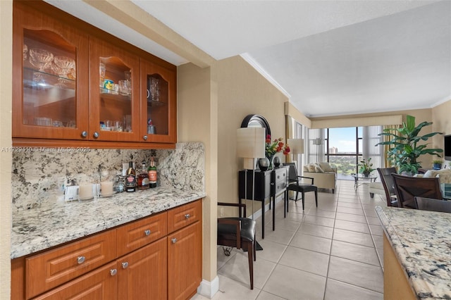 kitchen with light stone counters, light tile patterned flooring, crown molding, and tasteful backsplash