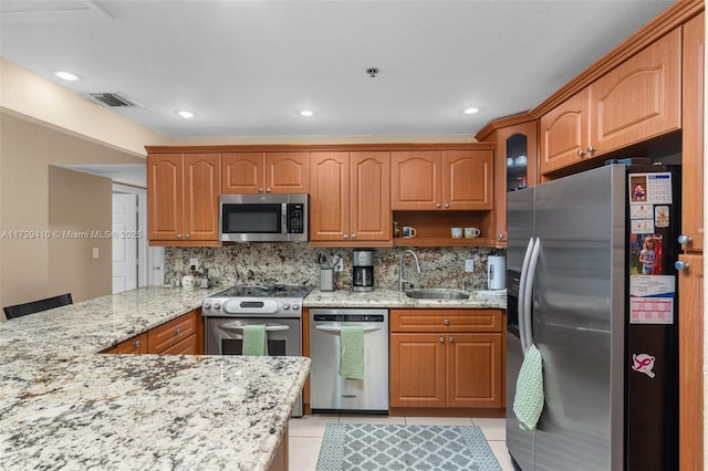 kitchen with kitchen peninsula, appliances with stainless steel finishes, sink, backsplash, and light tile patterned flooring