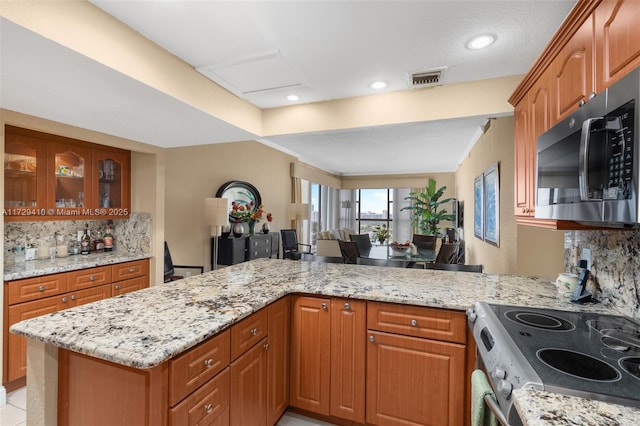 kitchen with stainless steel appliances, kitchen peninsula, and decorative backsplash