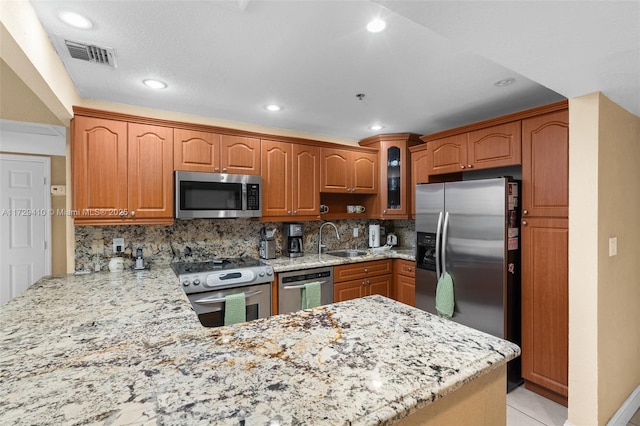 kitchen with stainless steel appliances, decorative backsplash, sink, kitchen peninsula, and light tile patterned flooring