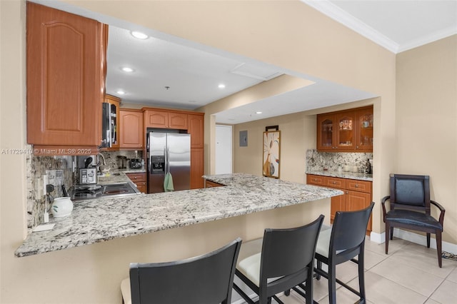 kitchen featuring a breakfast bar area, kitchen peninsula, appliances with stainless steel finishes, and decorative backsplash