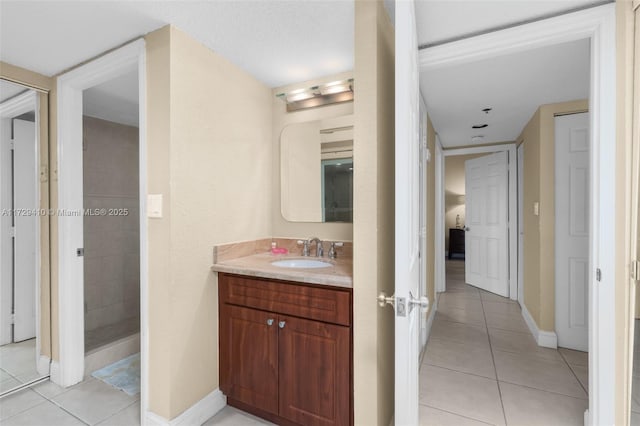 bathroom featuring a tile shower, tile patterned floors, and vanity