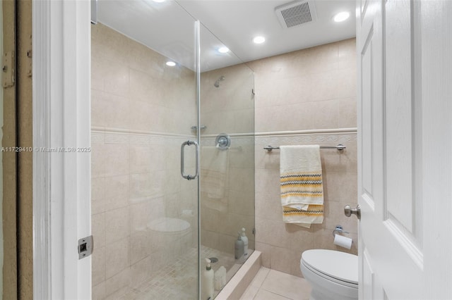 bathroom with tile patterned floors, toilet, walk in shower, and tile walls