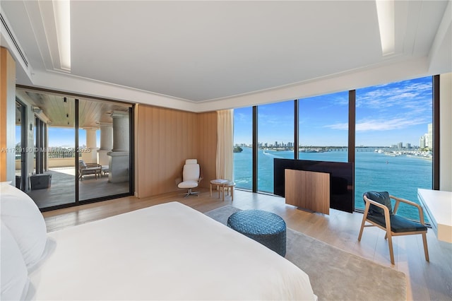 bedroom with a water view, access to exterior, multiple windows, and light wood-type flooring