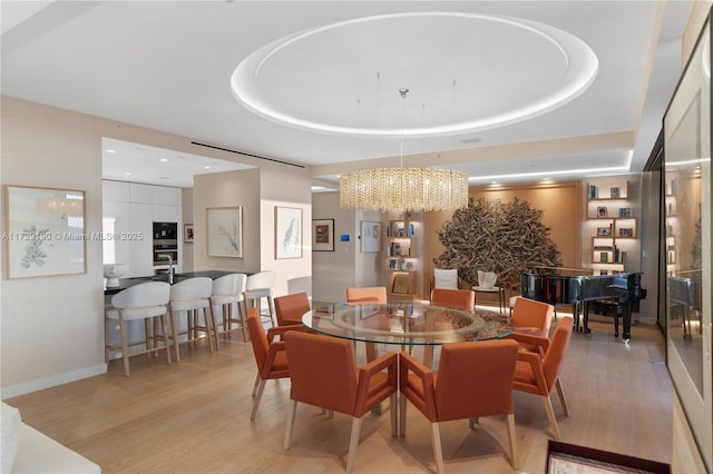 dining space featuring a tray ceiling and light hardwood / wood-style floors