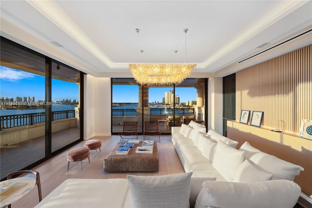 interior space featuring a notable chandelier, wood-type flooring, a raised ceiling, and a water view