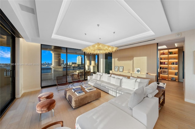 living room featuring floor to ceiling windows, an inviting chandelier, light hardwood / wood-style floors, and a tray ceiling