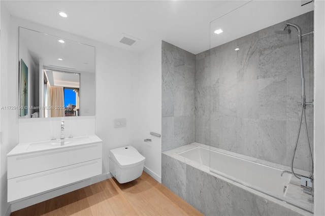 full bathroom with tiled shower / bath combo, wood-type flooring, vanity, and toilet