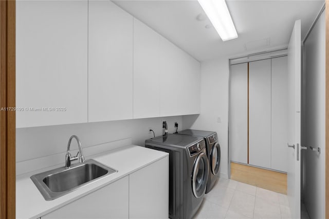 laundry area featuring cabinets, washer and clothes dryer, sink, and light tile patterned floors