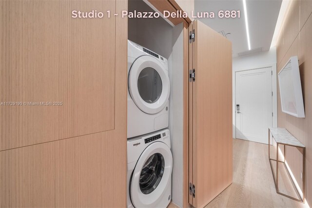 washroom with stacked washer / dryer and light hardwood / wood-style floors