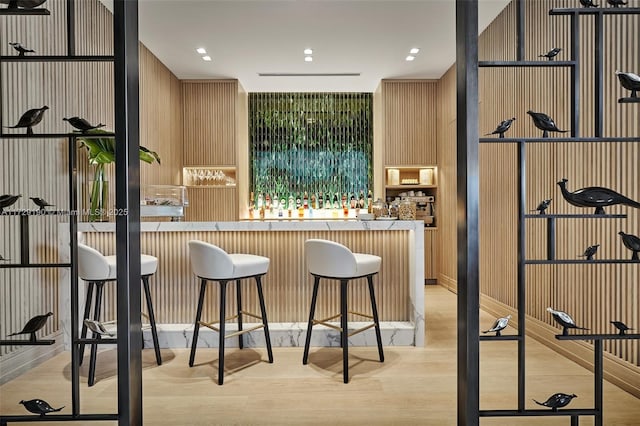 bar with wooden walls and light hardwood / wood-style flooring