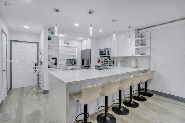 kitchen with appliances with stainless steel finishes, light wood-type flooring, a peninsula, and open shelves