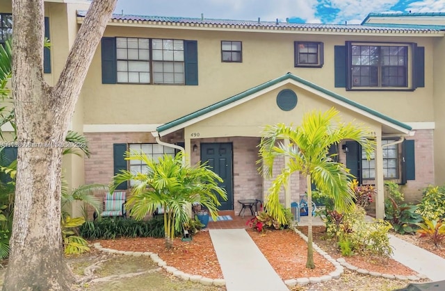 multi unit property featuring covered porch, brick siding, and stucco siding