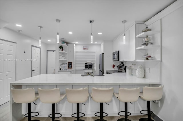 kitchen featuring appliances with stainless steel finishes, a peninsula, light countertops, white cabinetry, and open shelves