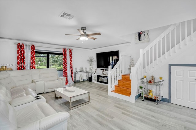 living room with light wood-style flooring, stairway, visible vents, and a ceiling fan