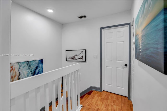 hall featuring baseboards, visible vents, wood finished floors, an upstairs landing, and recessed lighting