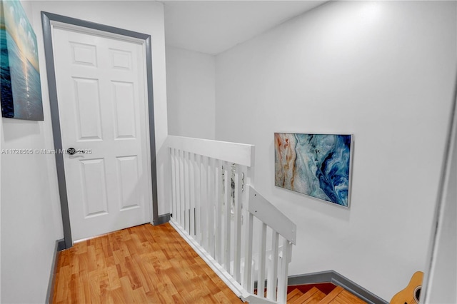 corridor featuring baseboards, an upstairs landing, and wood finished floors