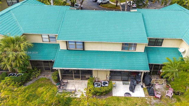 back of house featuring a tiled roof and stucco siding