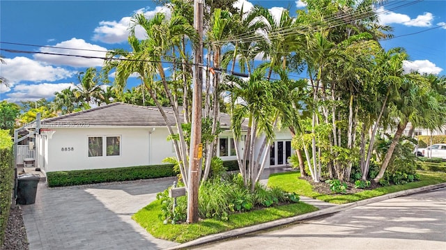 view of front facade featuring a tiled roof, french doors, and stucco siding