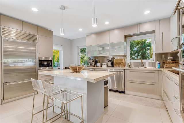 kitchen with light tile patterned flooring, backsplash, appliances with stainless steel finishes, and a center island